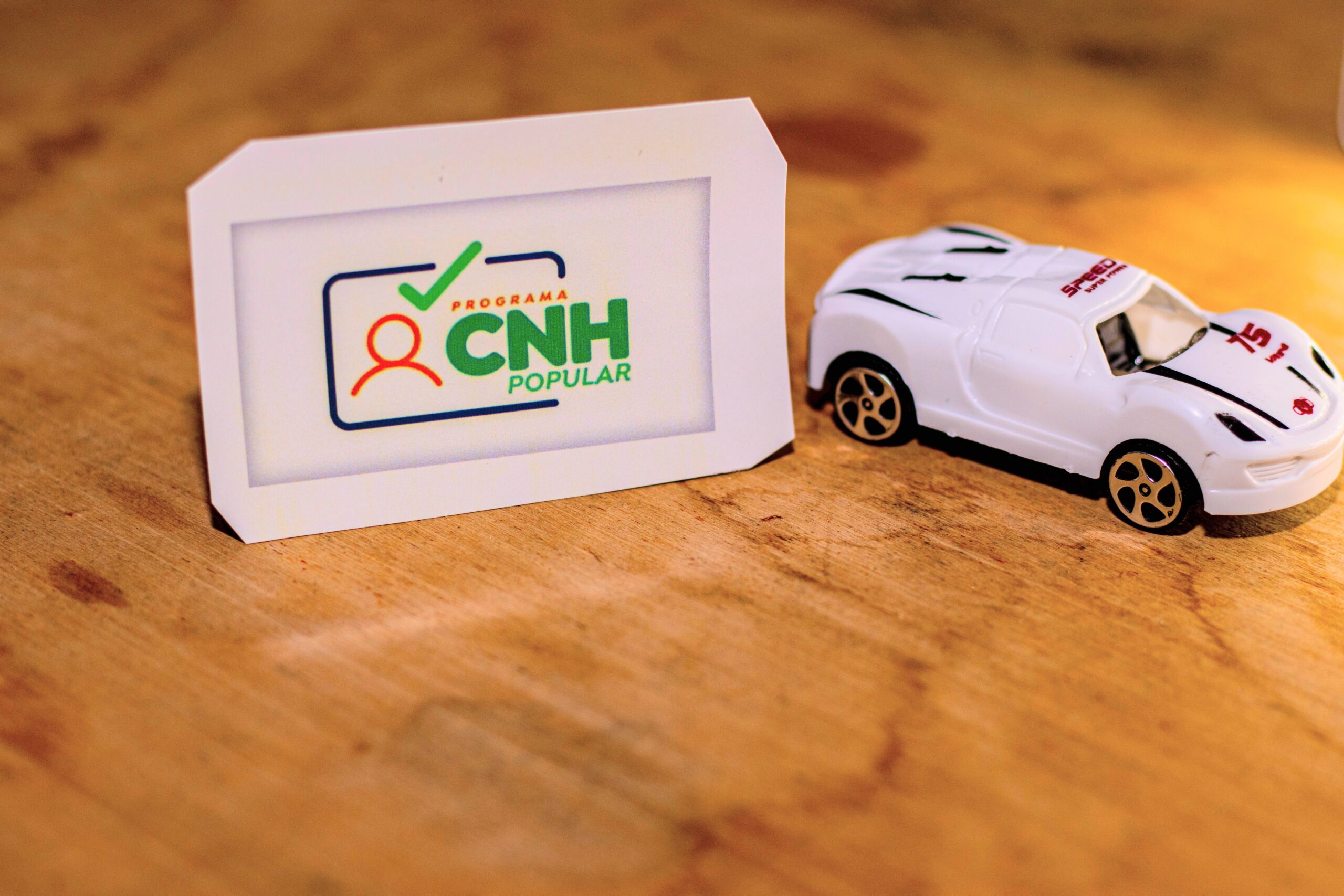 Papel escrito CNH popular e um pequeno carro ao lado