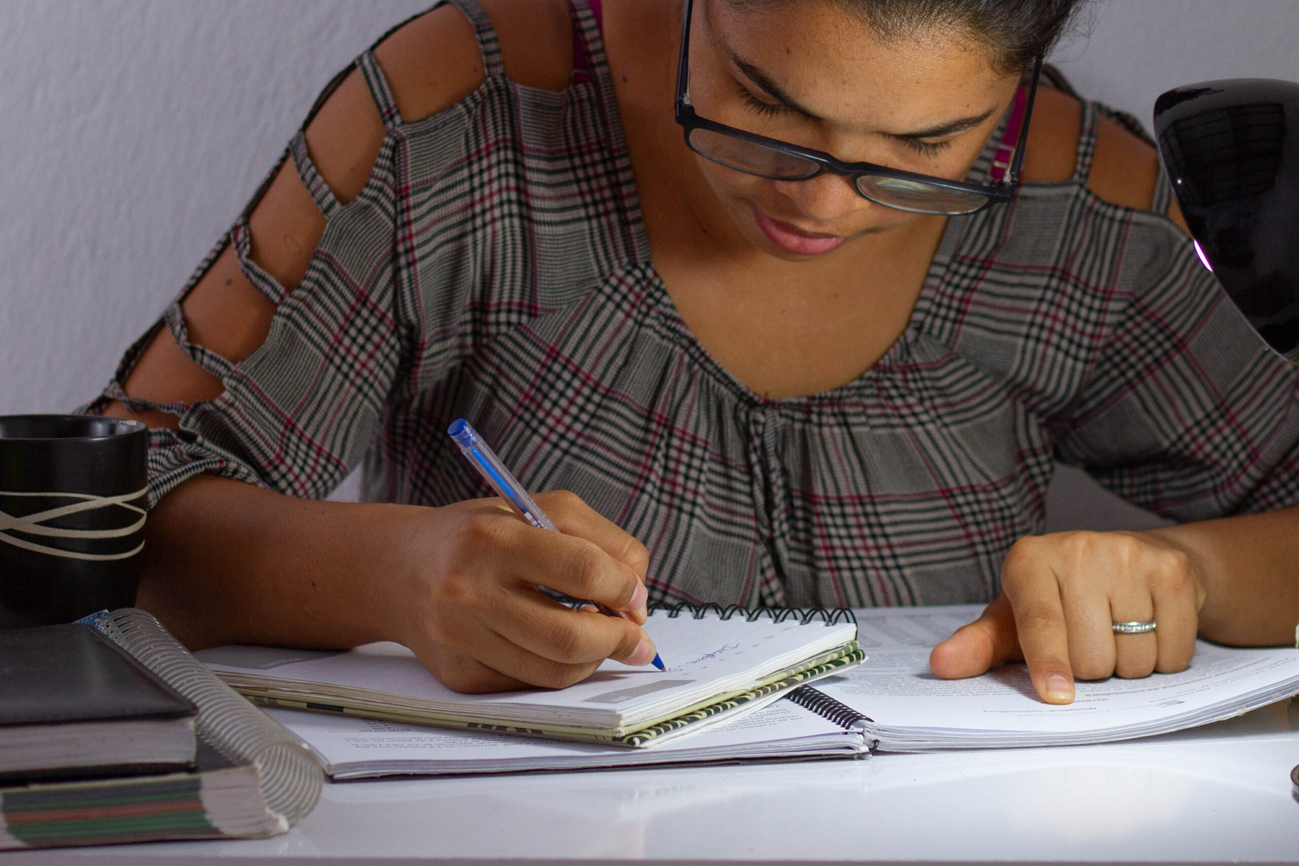 Mulher com uma caneta e papel na mão estudando