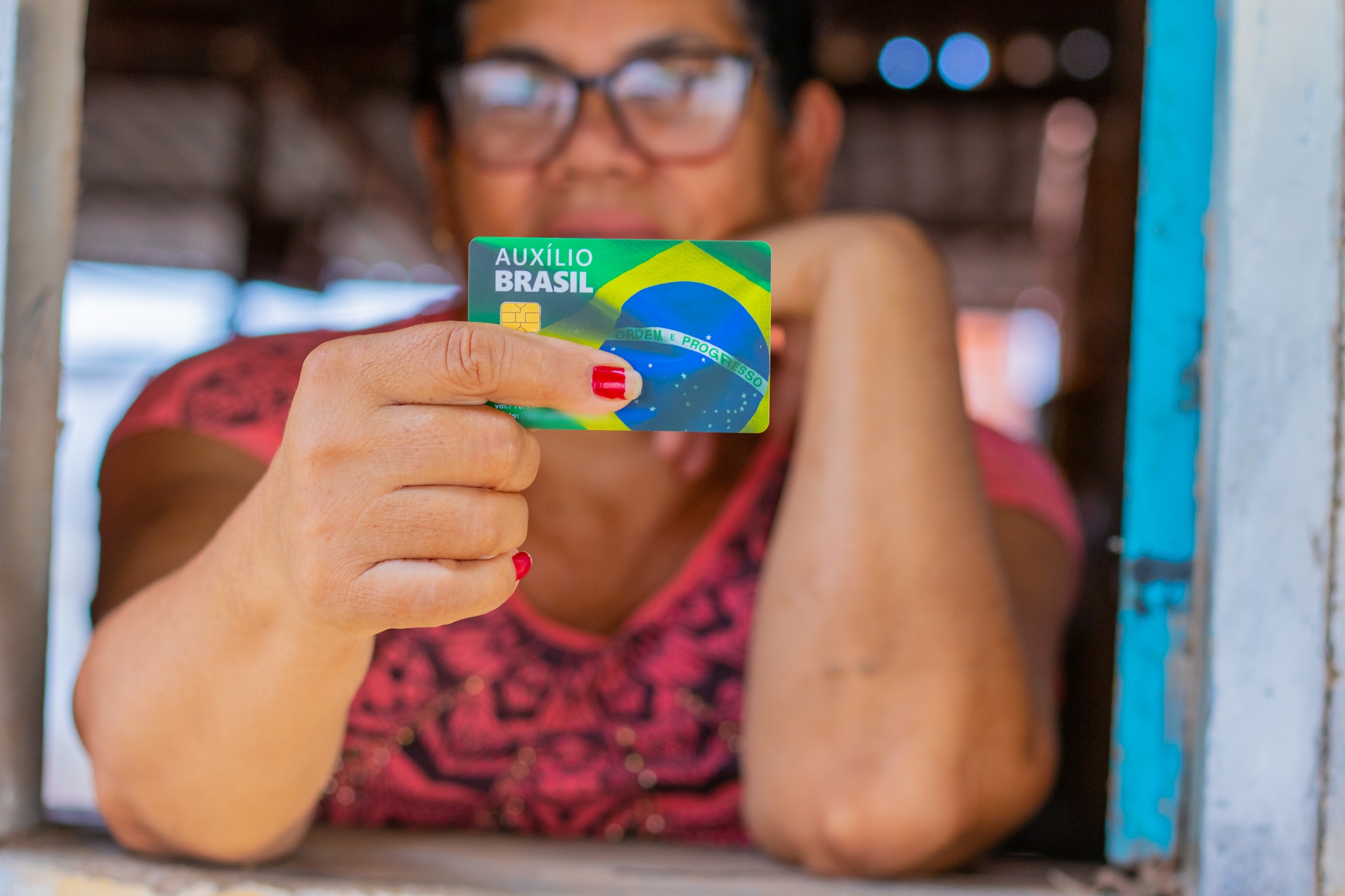 Mulher segurando um cartão referente a um benefício social