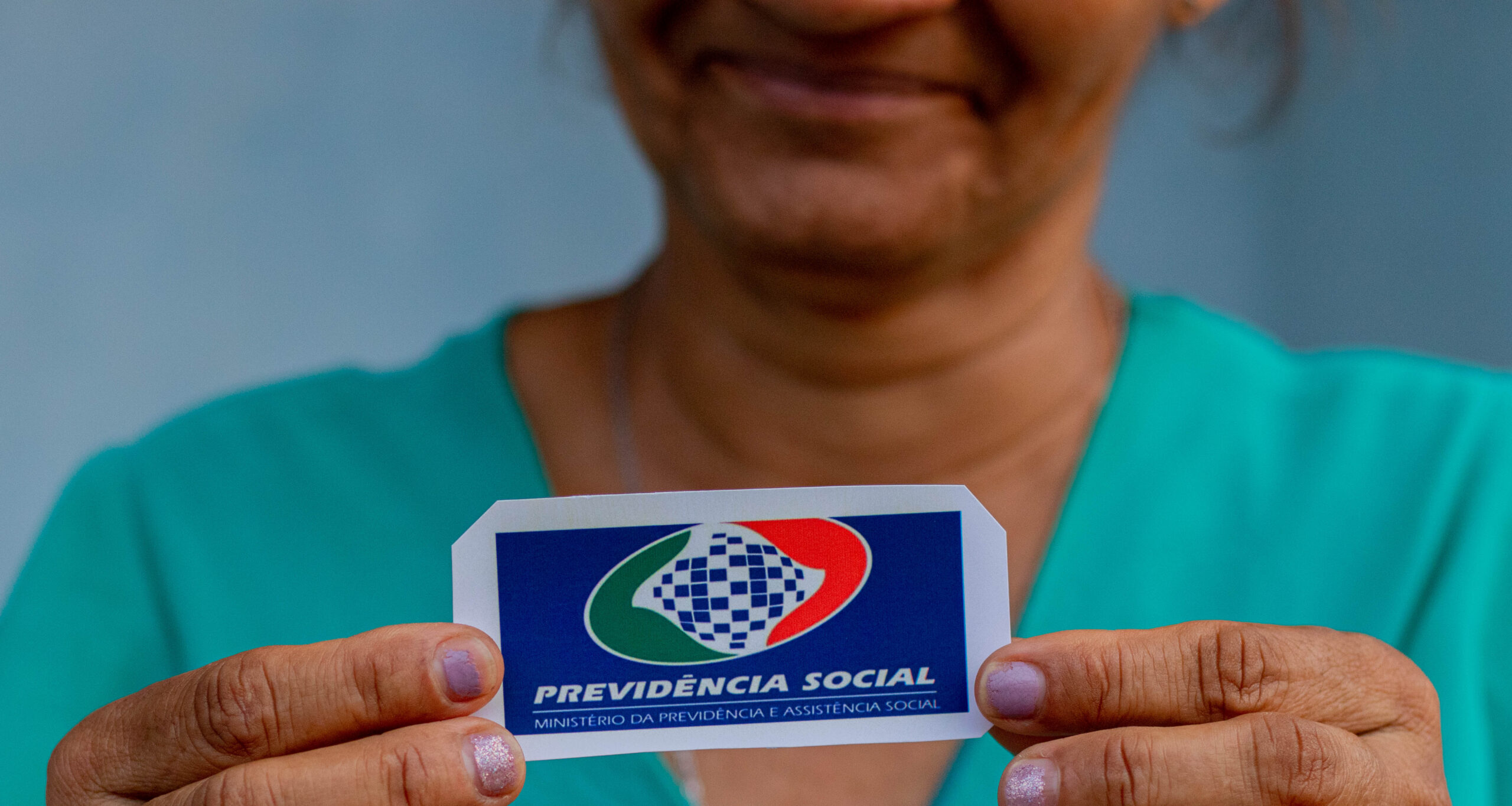 Idosa segurando um papel em sua mão escrito 'Previdência Social