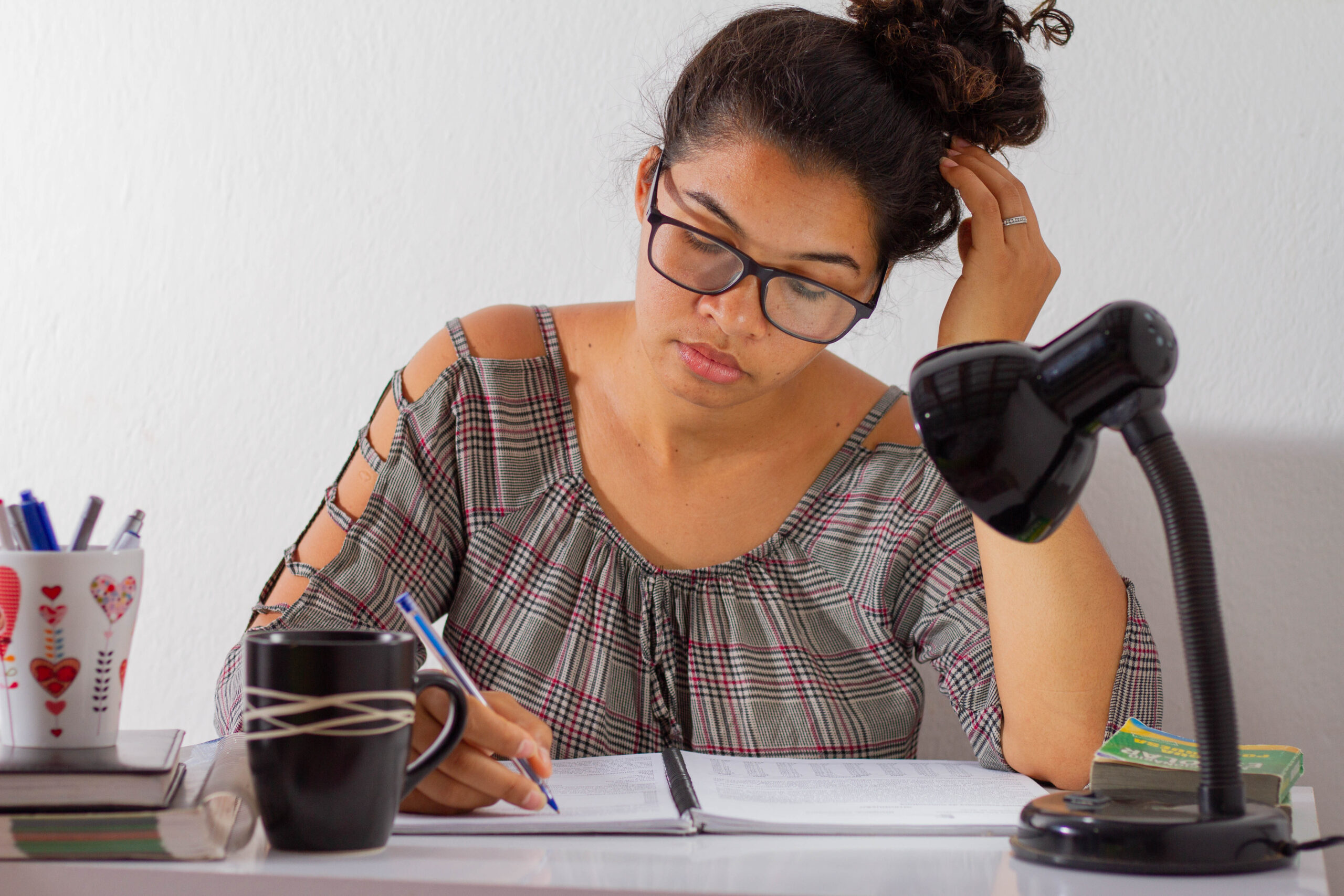 Jovem lendo uma folha de caderno enquanto estuda