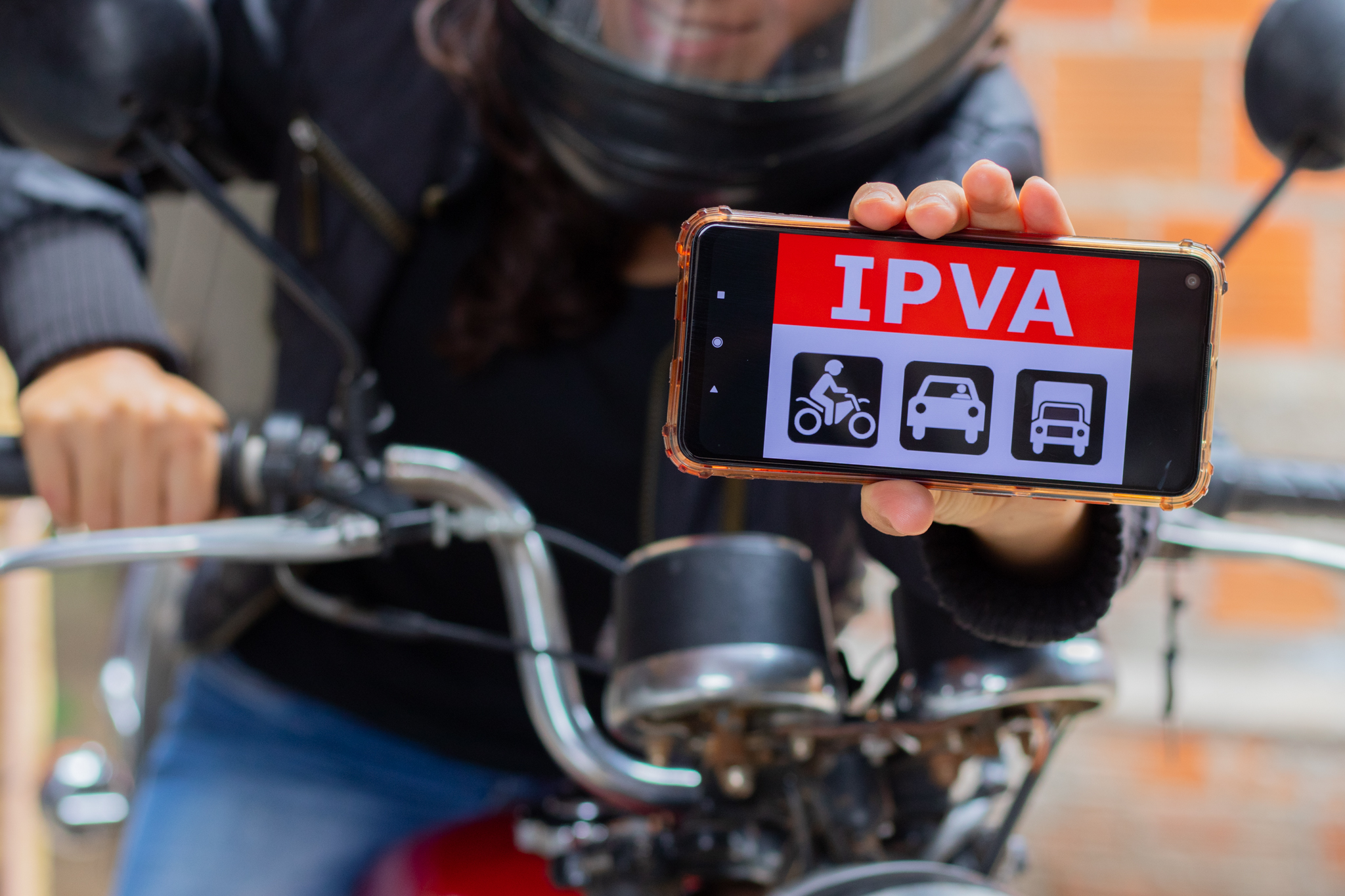 Motorista mostrando o celular com um papel de parede escrito 'IPVA'