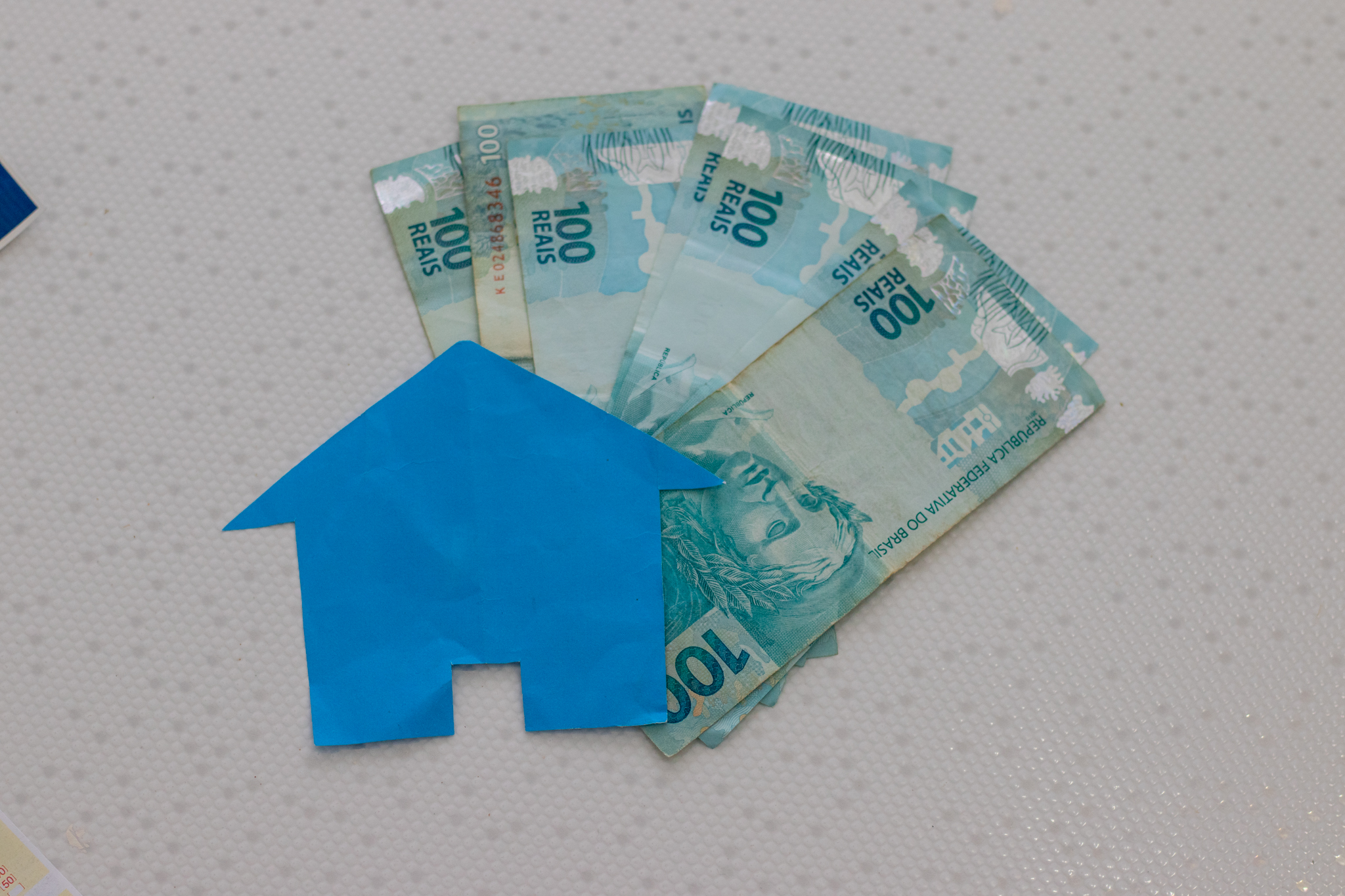 Várias cédulas de dinheiro brasileiro e uma casa feita de papel