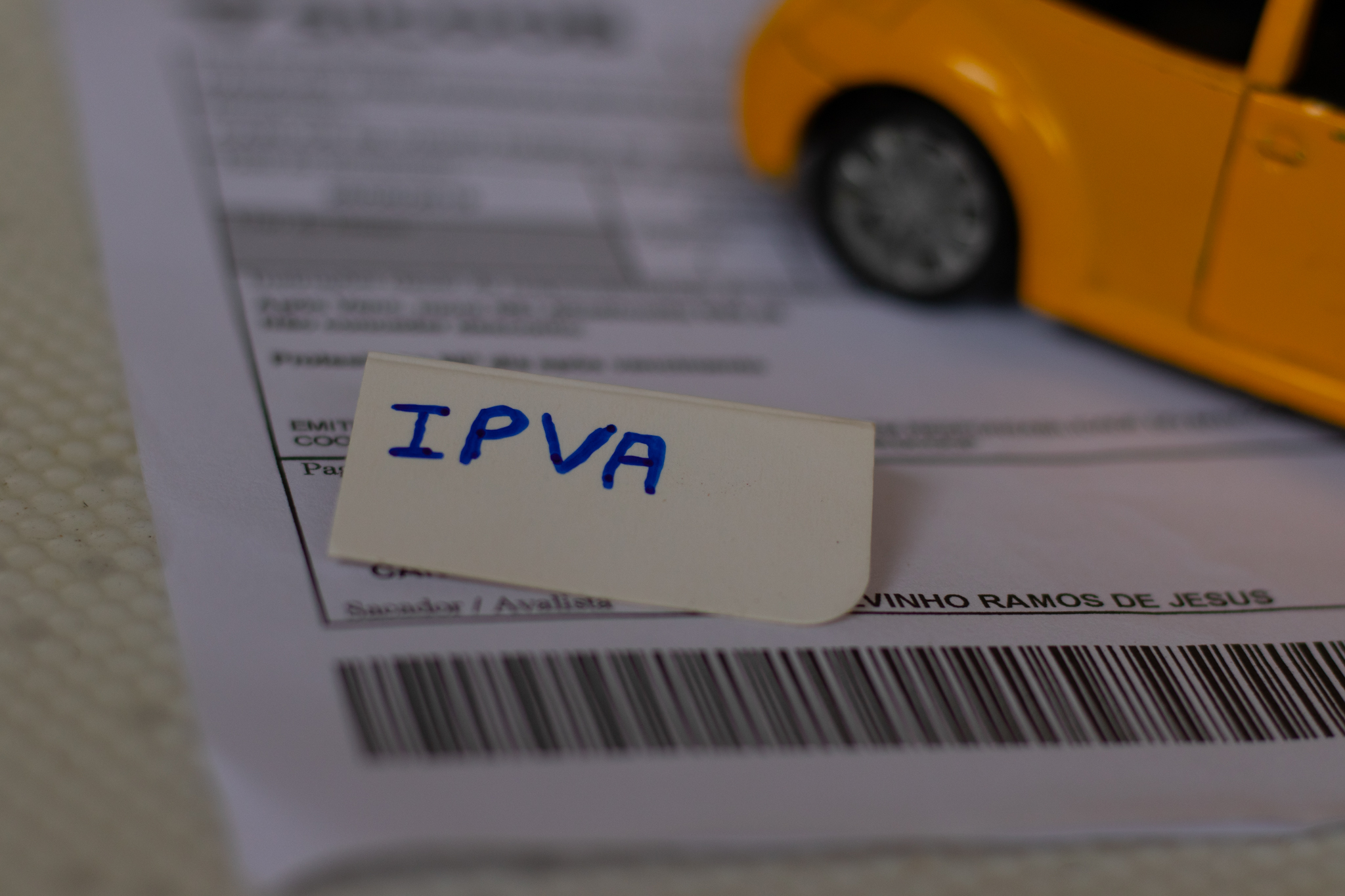 Carro em cima de um boleto de cobrança do IPVA