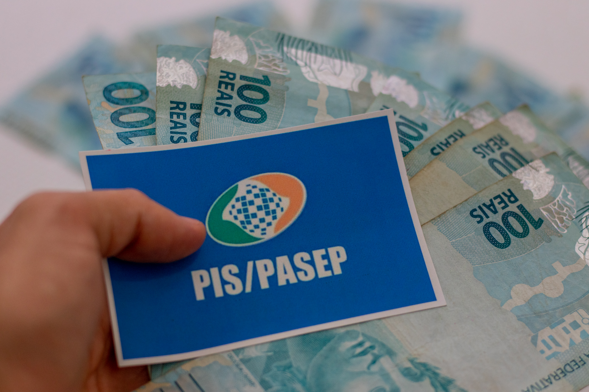 Pessoa segurando um papel com o nome 'PIS/PASEP'.