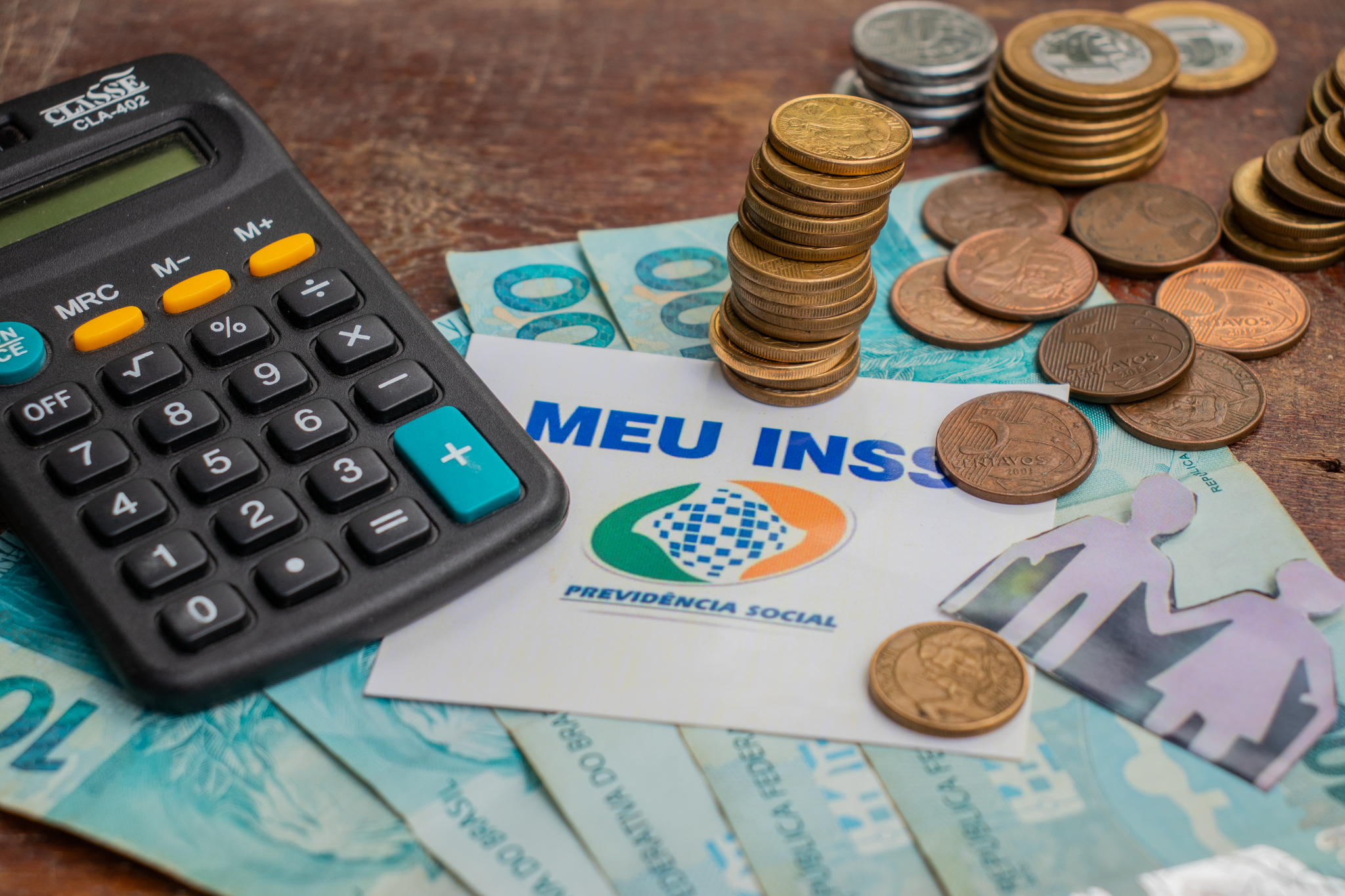 Calculadora, cédulas de dinheiro brasileiro e o nome Meu INSS