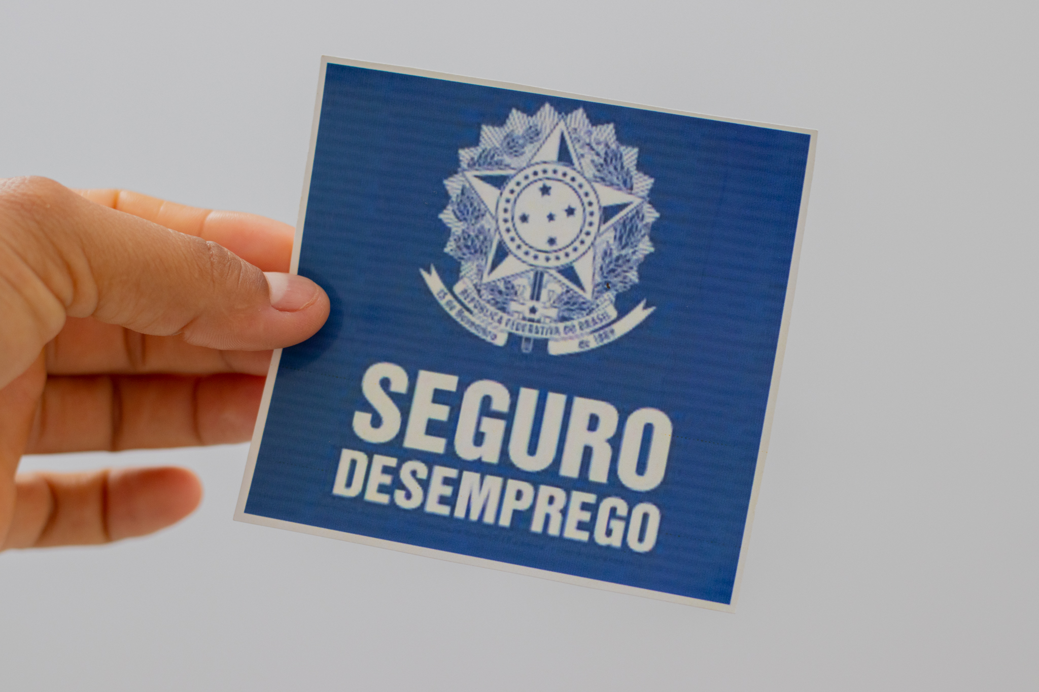 Pessoa segurando um papel com o nome 'seguro-desemprego'