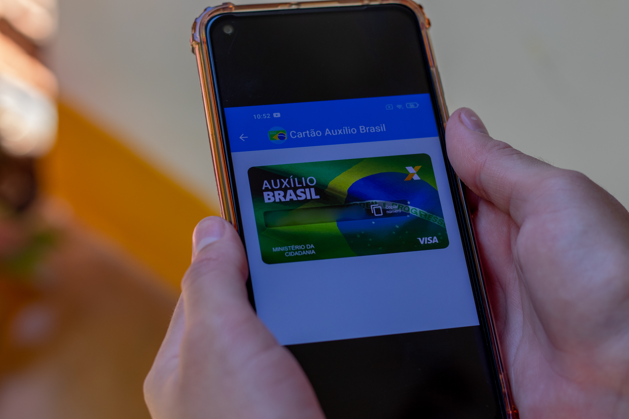 Pessoa olhando o cartão do auxílio brasil