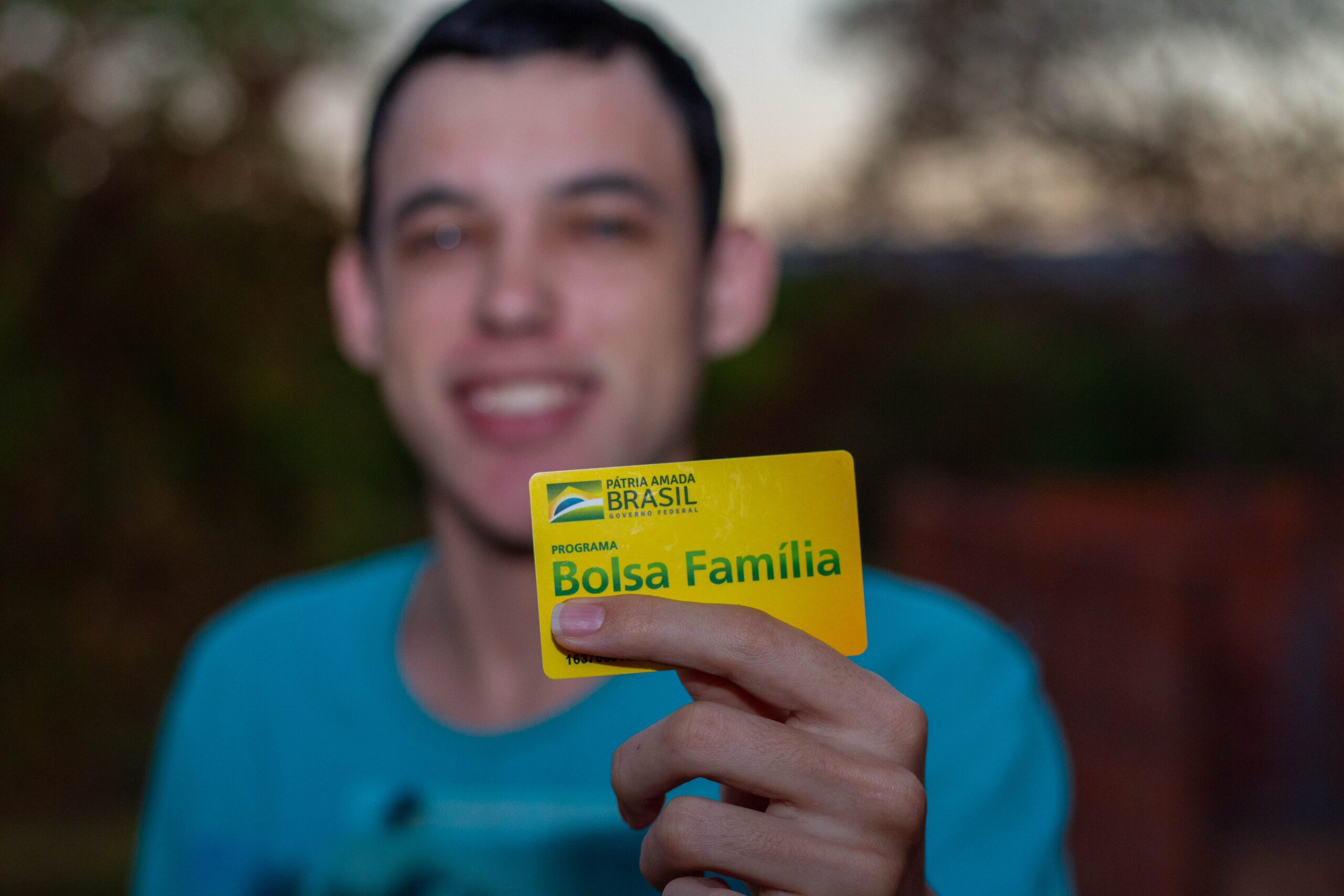 Rapaz segurando cartão do Bolsa Família