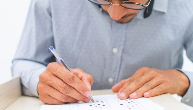 Pessoa resolvendo prova de concurso