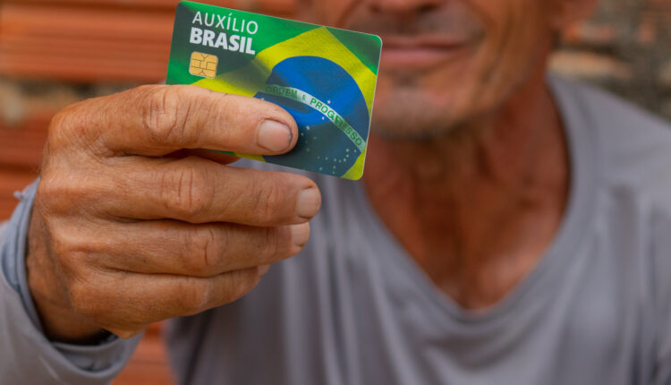 Homem segurando cartão do Auxílio Brasil
