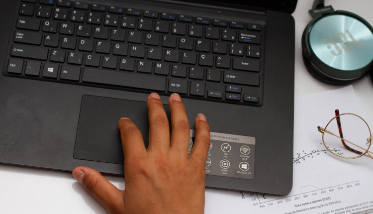 Foto de mão mexendo em um notebook.