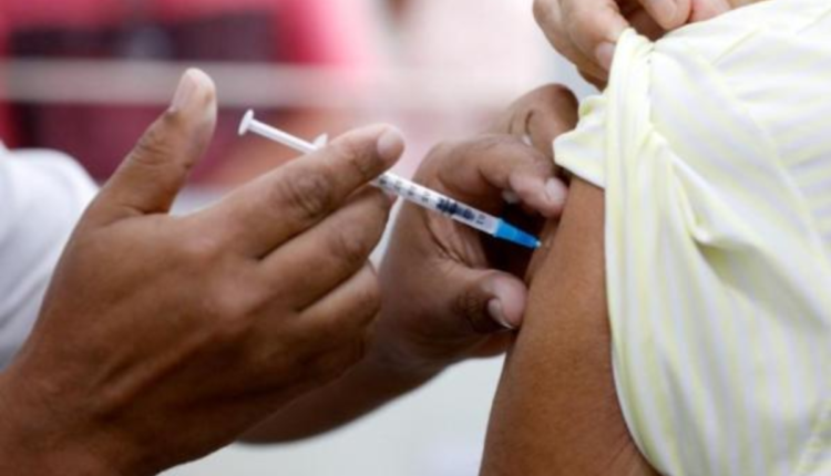 Profissional realizando a vacinação em braço de paciente.