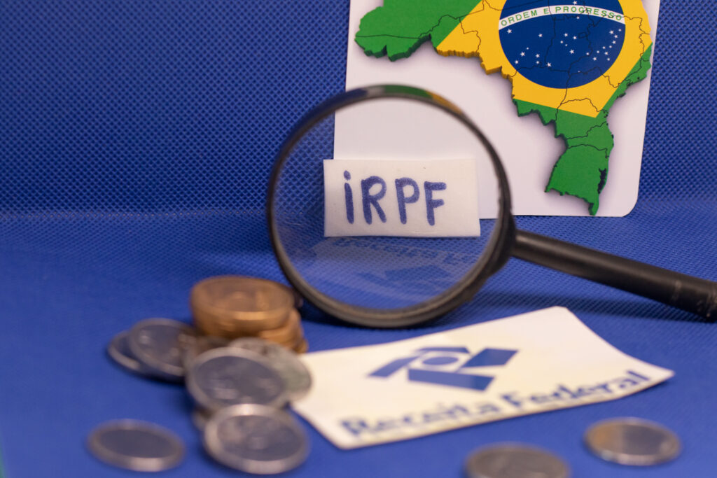 Papel escrito IRPF com moedas ao lado.