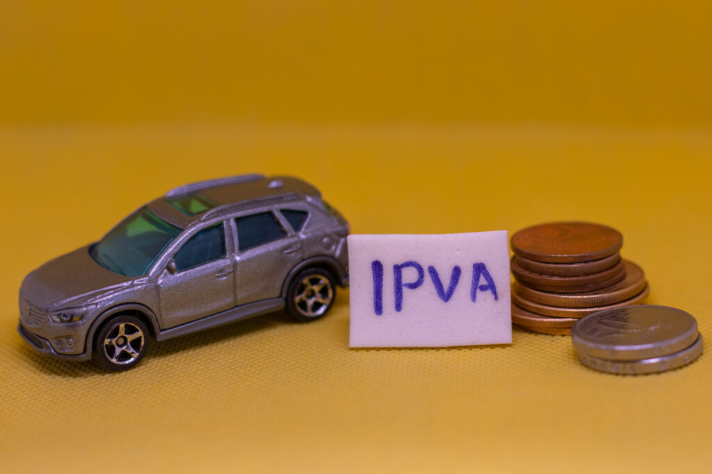 Carro de brinquedo ao lado de moedas e placa de IPVA.