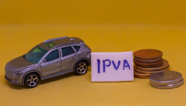 Carro de brinquedo ao lado de moedas e placa de IPVA.