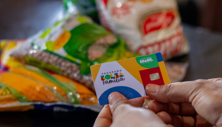 Cartão do bolsa família a frente de uma cesta básica.