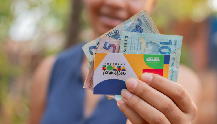 Mulher mostrando seu cartão do Bolsa Família para câmera.