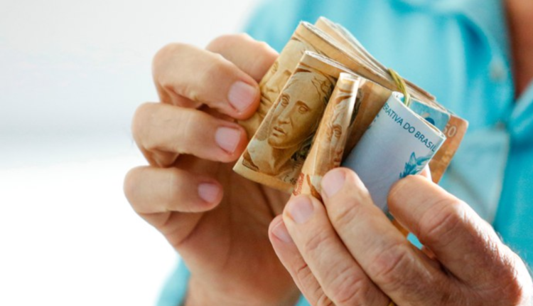 Pessoa com notas na mão, contabilizando um salário.