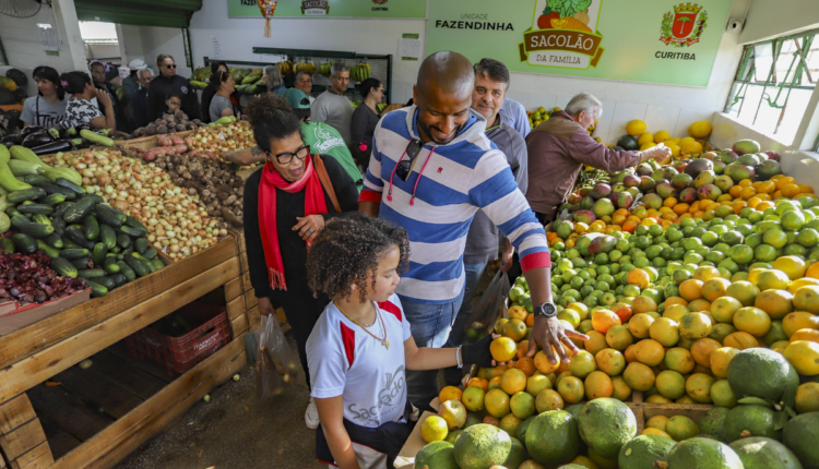 Pessoas realizando compra em sacolão.
