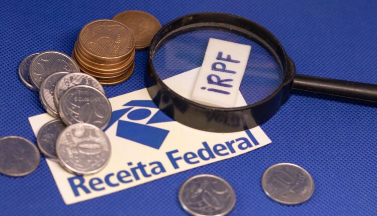 Moedas e placa do IRPF e Receita Federal.
