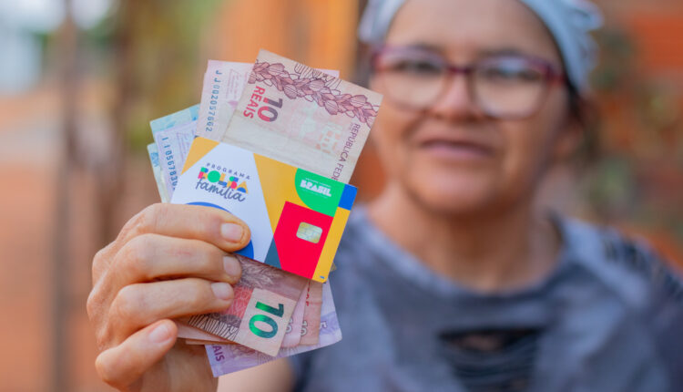 Mulher mostrando cartão do Bolsa Família.