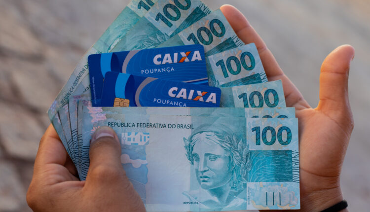 Notas de dinheiro e cartões da Caixa.