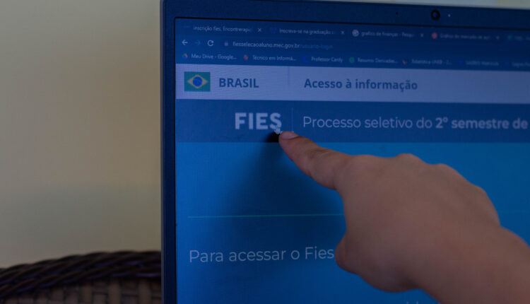 Pessoa apontando para tela de Notebook.