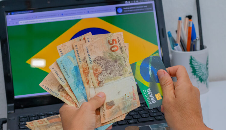 Pessoa segurando dinheiro e cartão.