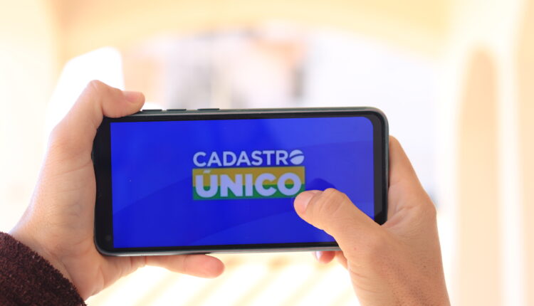 Pessoa segurando celular na horizontal no app CadÚnico.