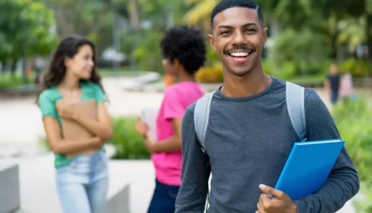 Estudante segurando caderno, sorrindo.