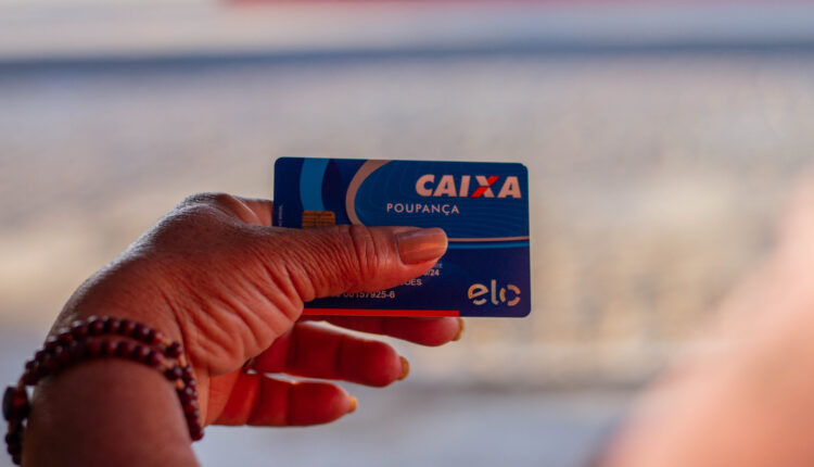 Pessoa mostrando cartão da Caixa.