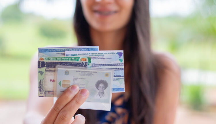 Mulher segurando vários documentos, incluindo o RG.