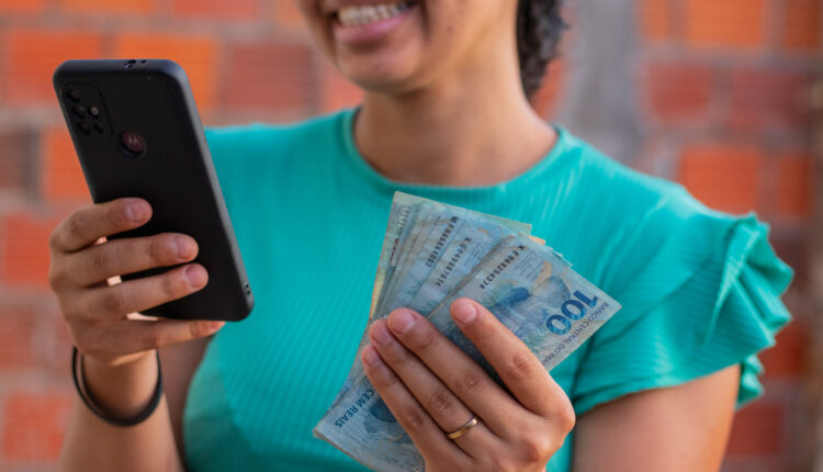 Mulher meia idade com celular na mão ganhando dinheiro.