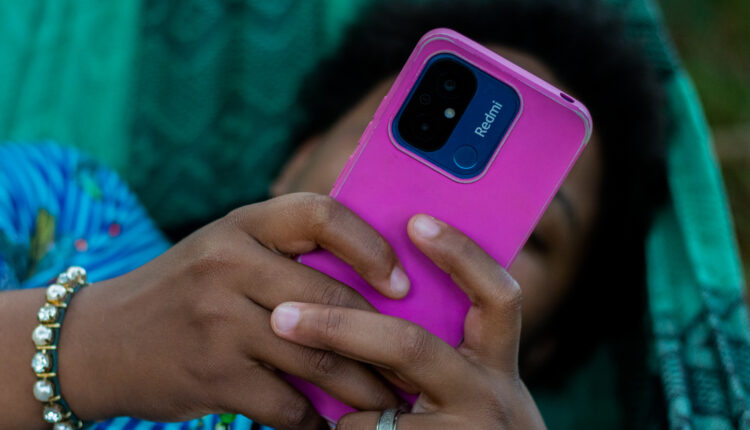 Mulher deitada mexendo no celular.