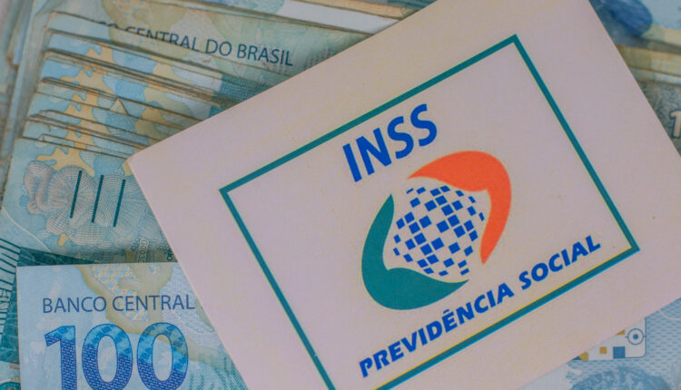Dinheiro em mesa, logo do INSS.