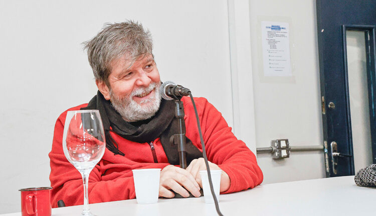 Homem diante de um microfone, sorrindo.
