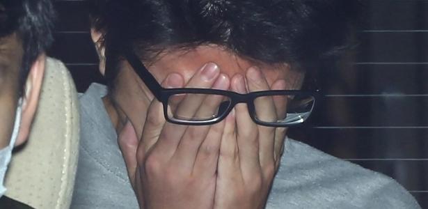 Takahiro Shiraishi cobre o rosto com as mãos enquanto é transportado de uma delegacia de polícia em Tóquio para o Ministério Público. em 2017