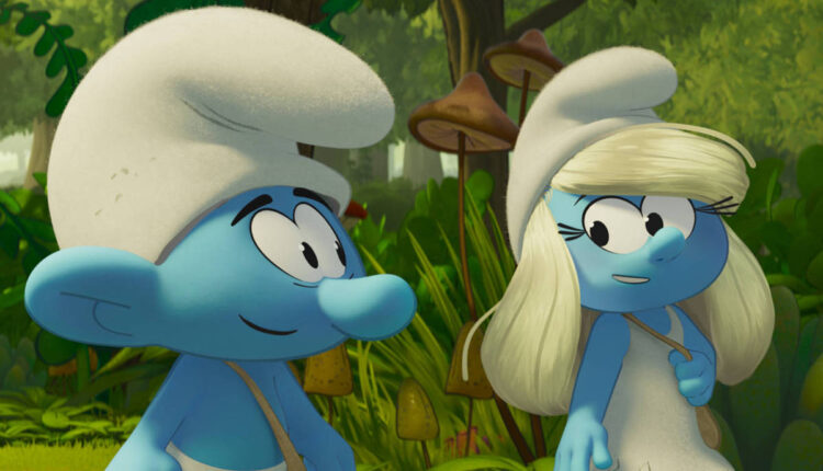 A imagem mostra dois Smurfs em um ambiente de floresta. Um Smurf tem pele azul e usa um chapéu branco, enquanto a Smurfete também tem pele azul e cabelo loiro, usando um vestido branco. Ao fundo, há vegetação densa e árvores, criando um cenário natural.