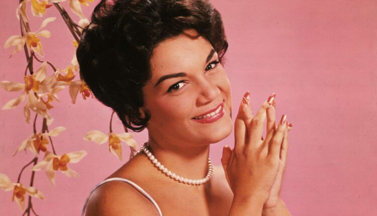 Studio portrait of American singer Connie Francis wearing a lavender and white spaghetti-strap dress.