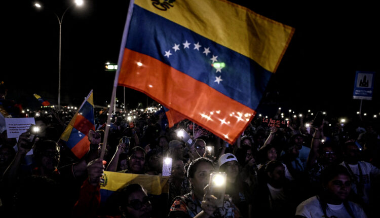 Apoiadores do presidente da Venezuela, Nicolás Maduro, agitam uma bandeira venezuelana durante um ato em defesa da paz em Caracas